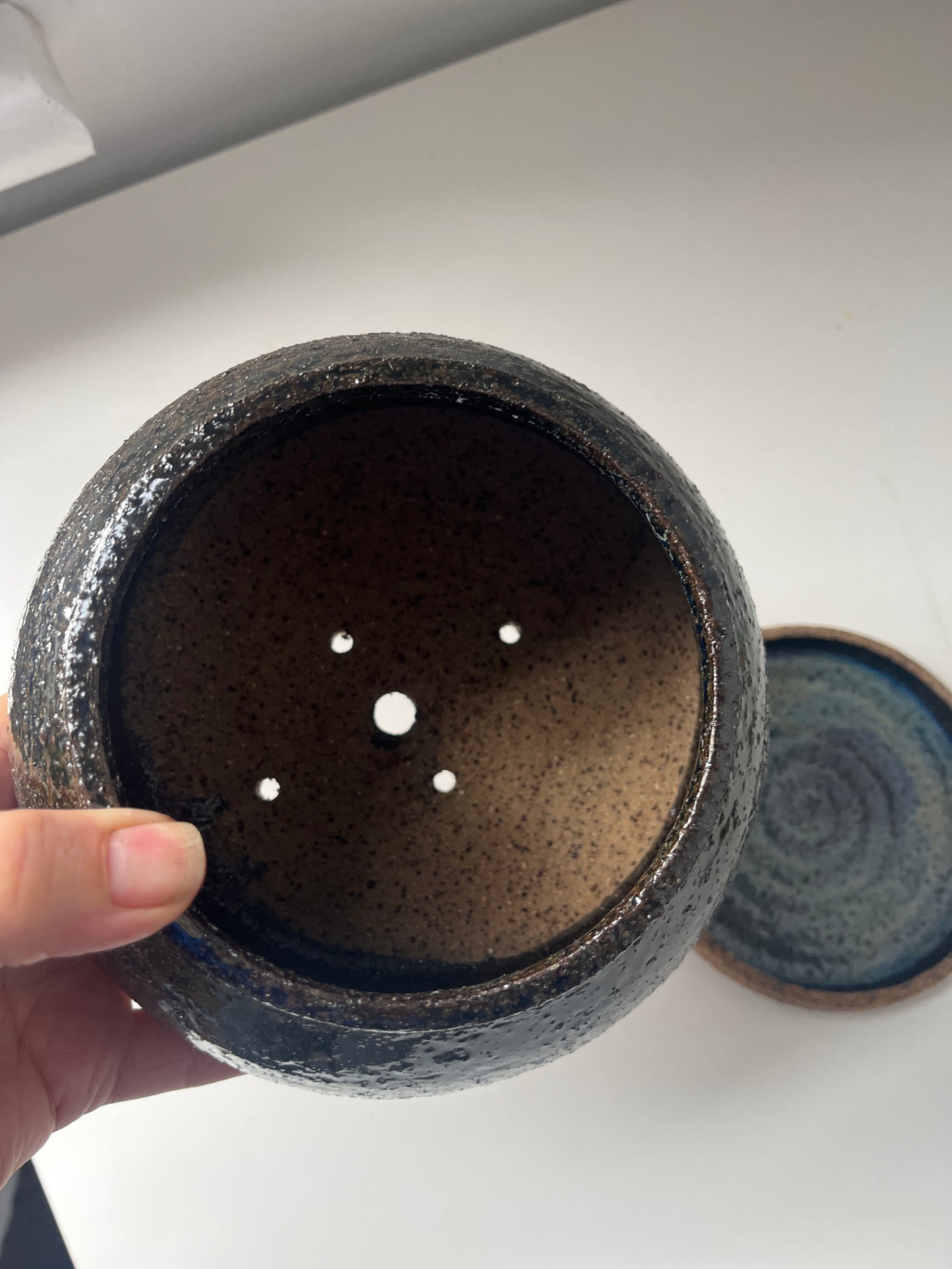 Ceramic pot with small holes on a white background