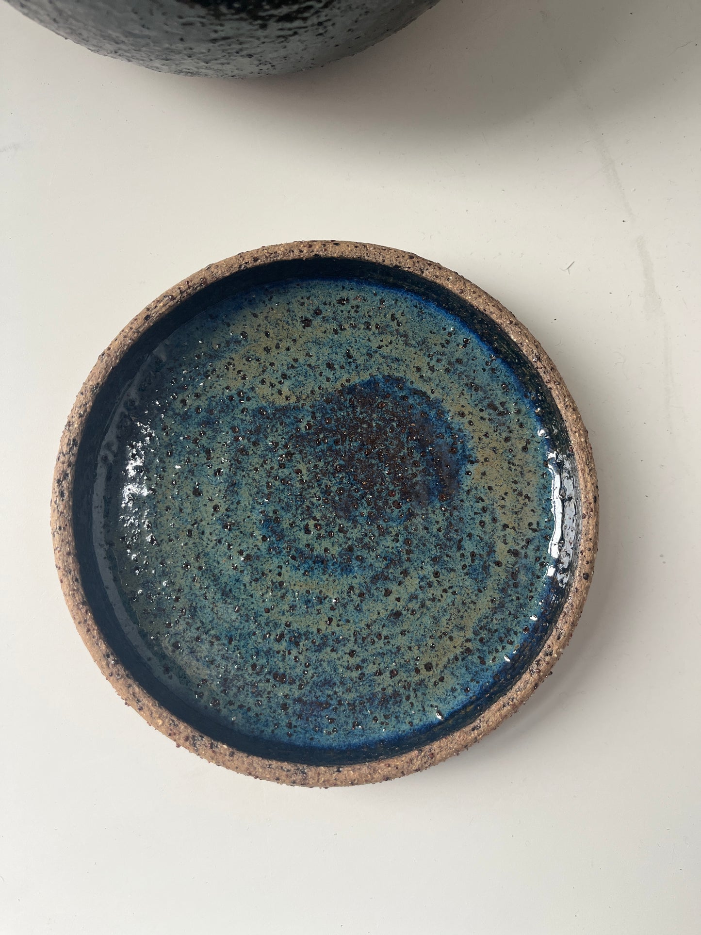 Ceramic bowl with blue black speckled glaze on a white background
