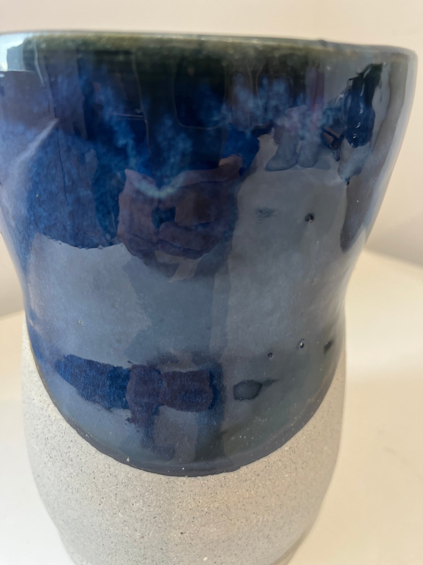 Ceramic vase with blue glaze and gray speckled clay on a white background