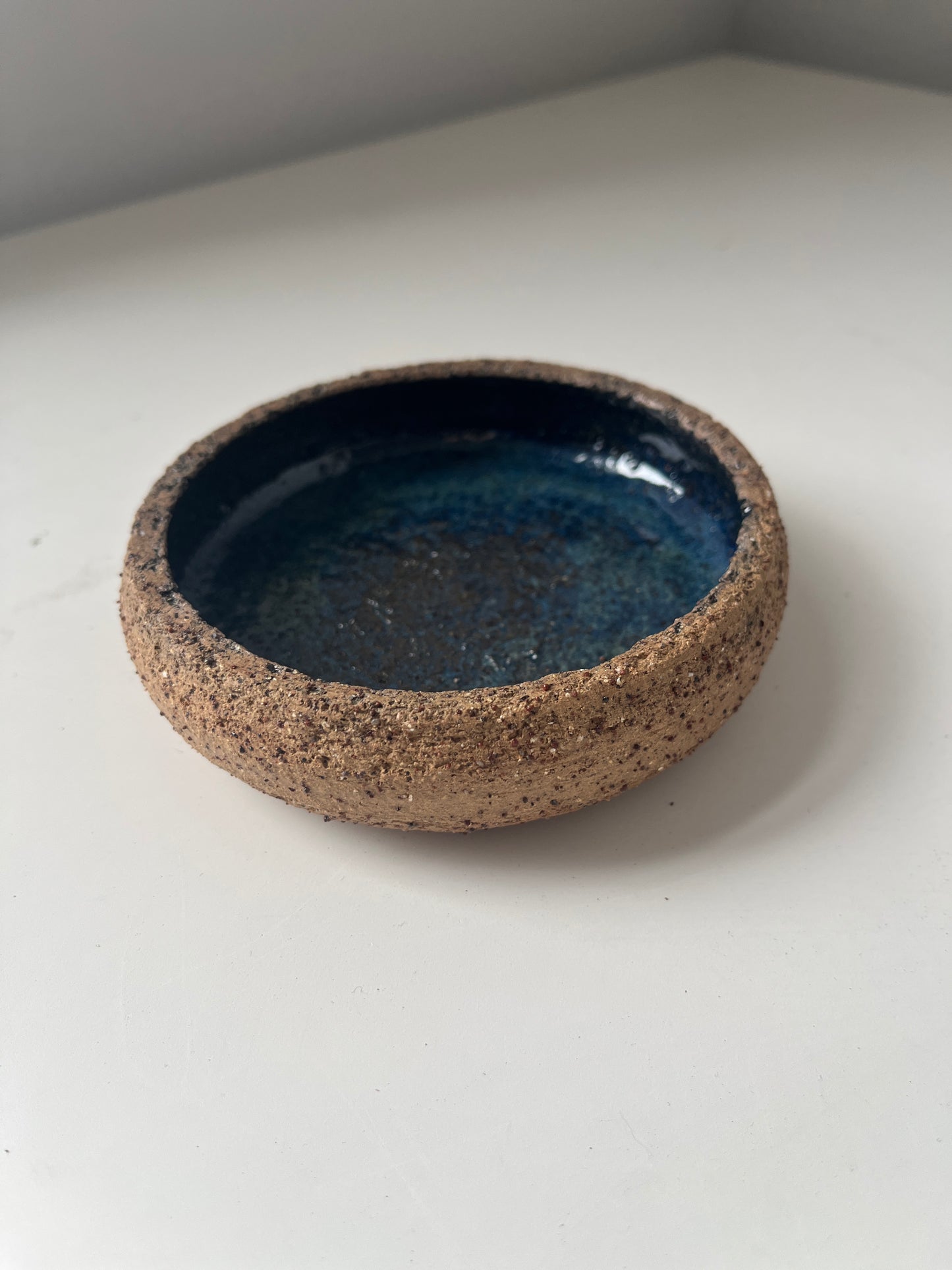 Ceramic dish with blue interior and brown exterior on a white background