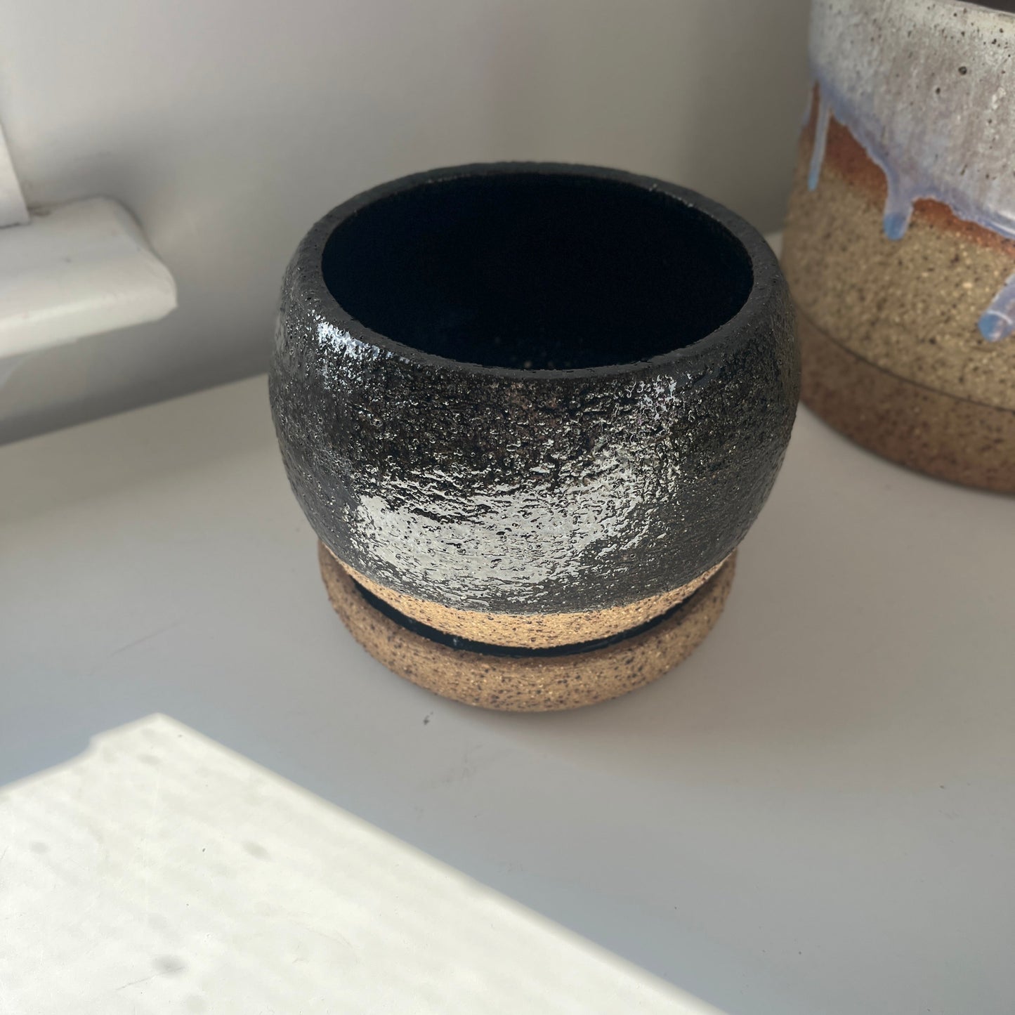 One ceramic pots on a white surface with a neutral background