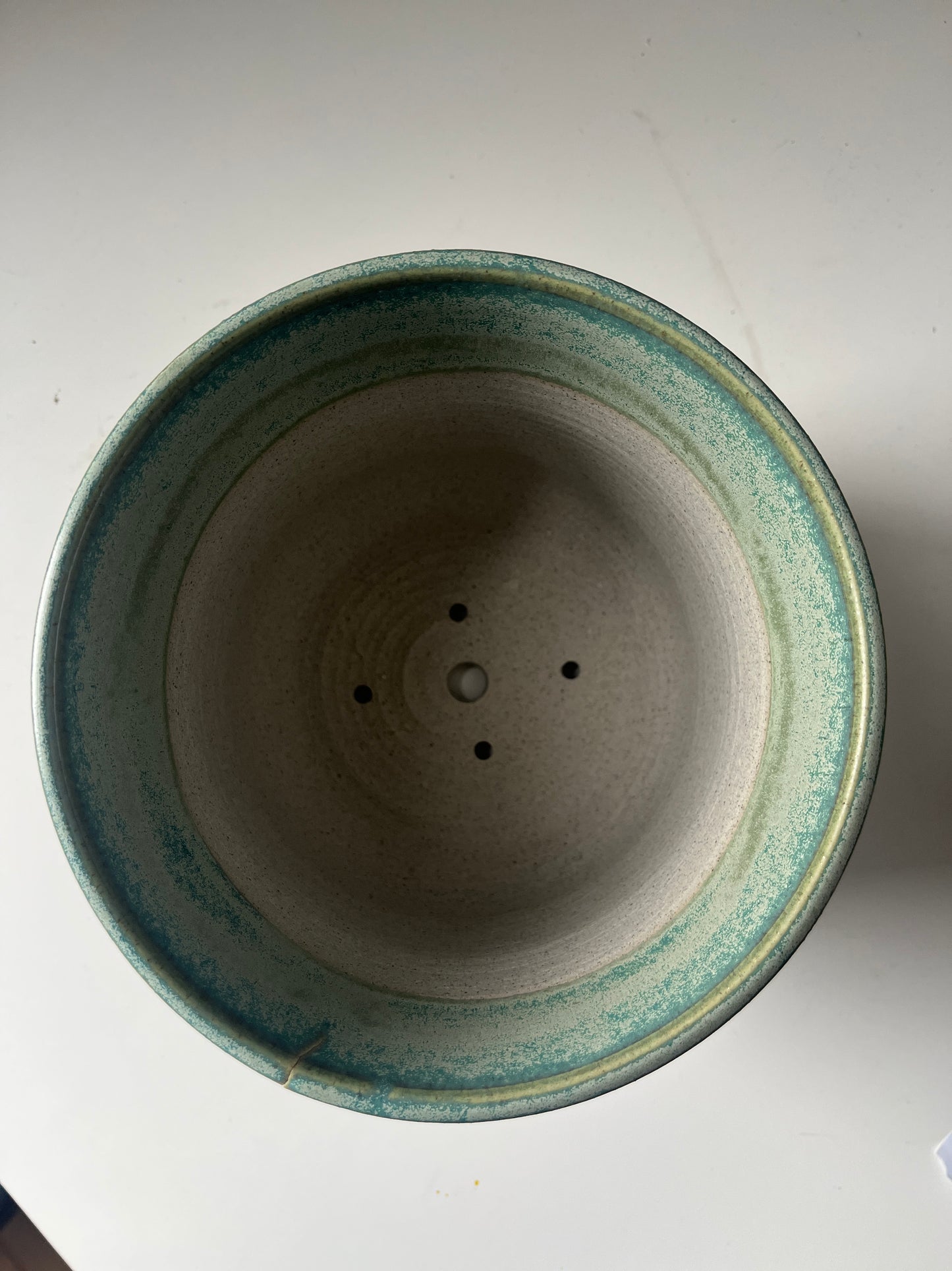 Ceramic pot with green rim on a white background