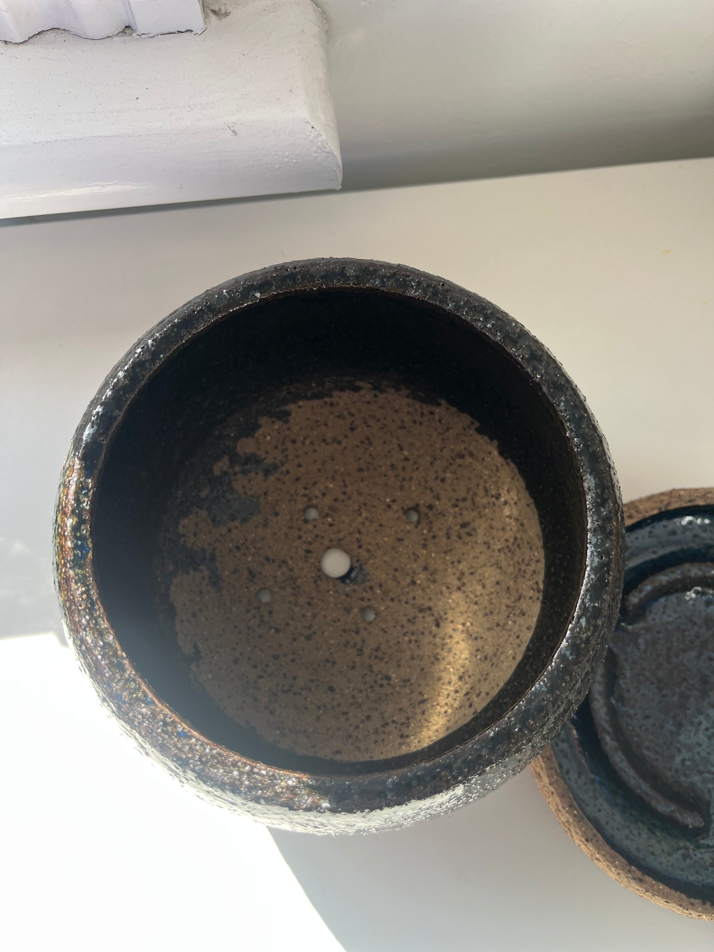Black ceramic pot with a rustic interior on a light background