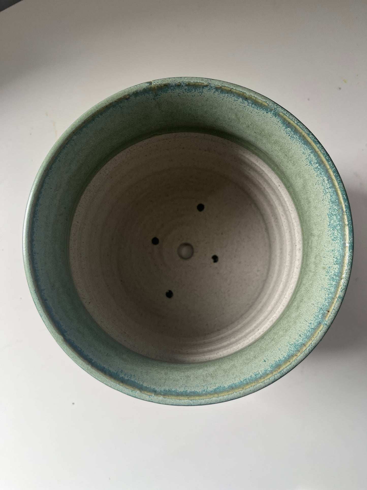 Ceramic pot with green rim on a white background