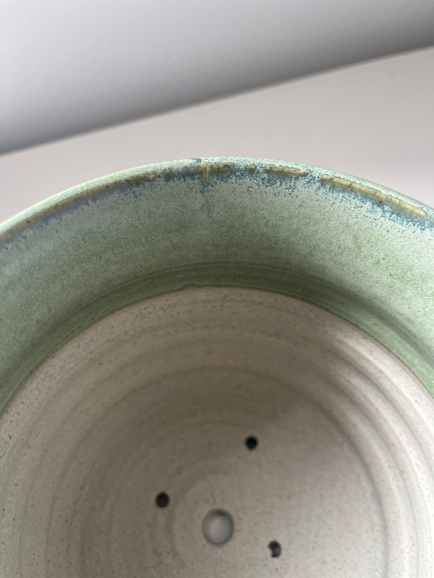 Close-up of a ceramic pot with a small crack on rim on a light background