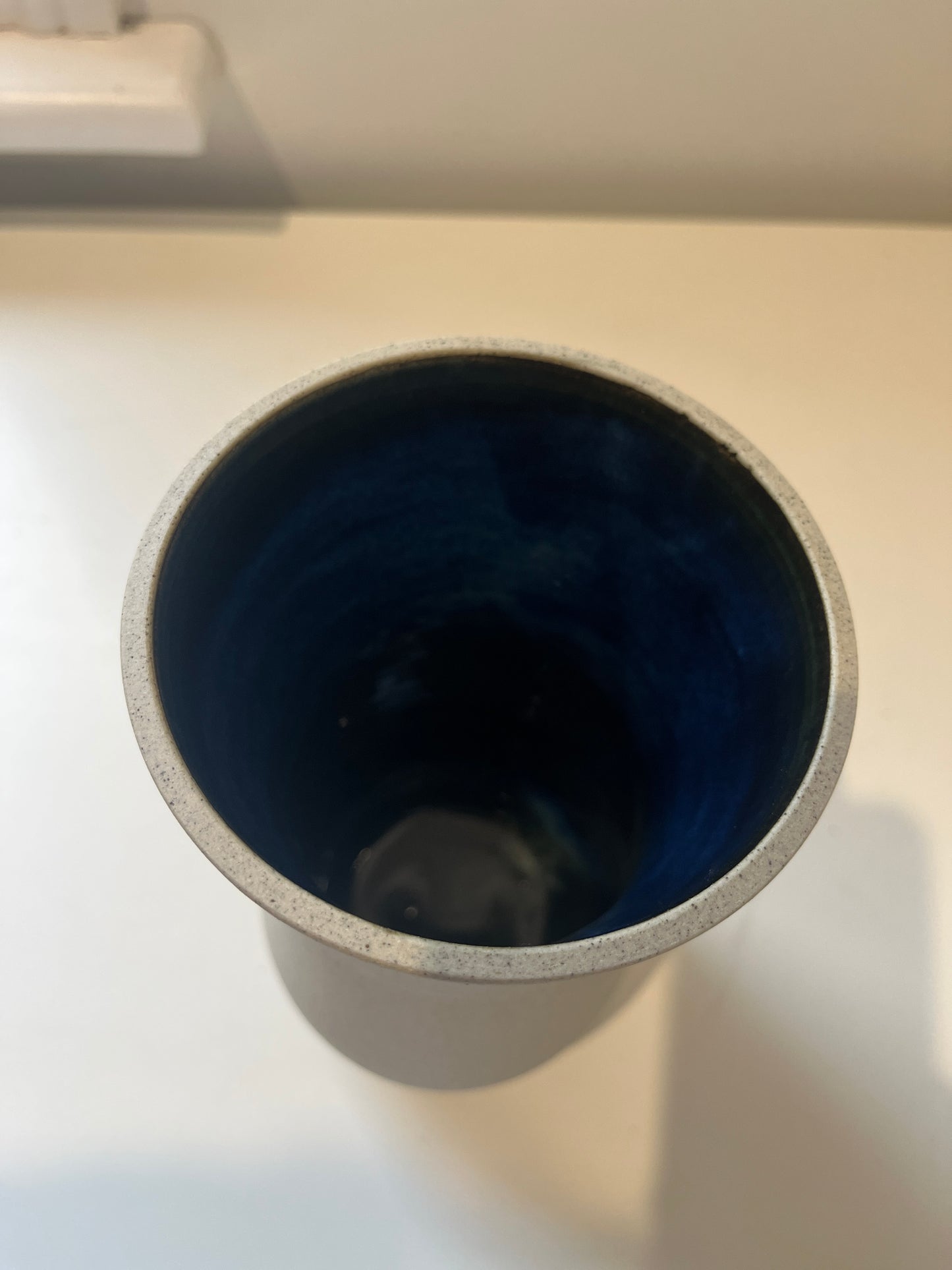 Blue interior of a raw clay vase on a white background.