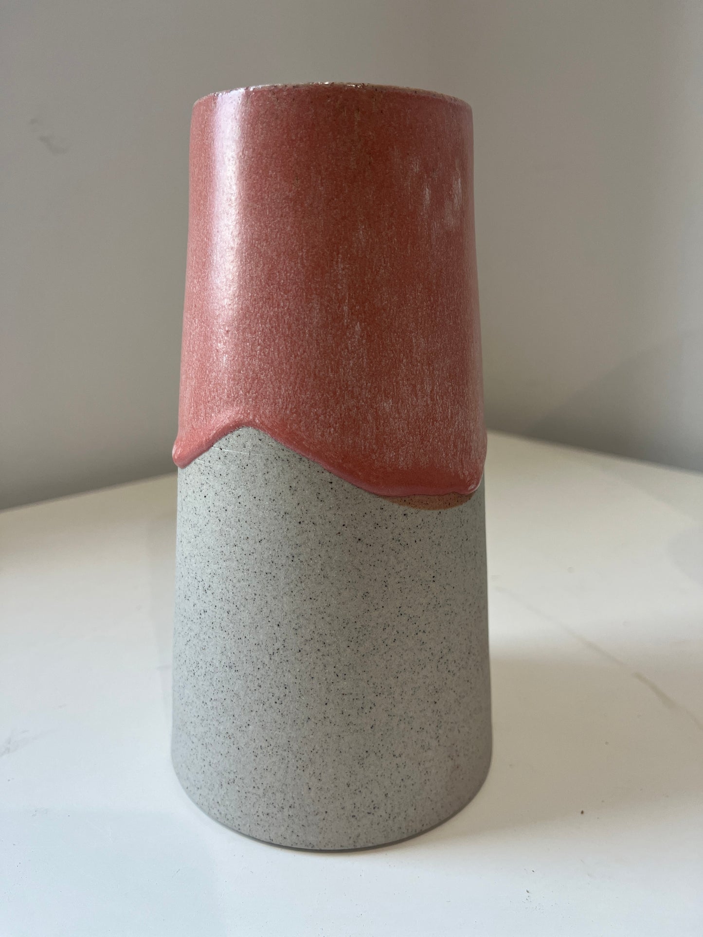 Cylindrical ceramic vase with two-tone design on a white surface.
