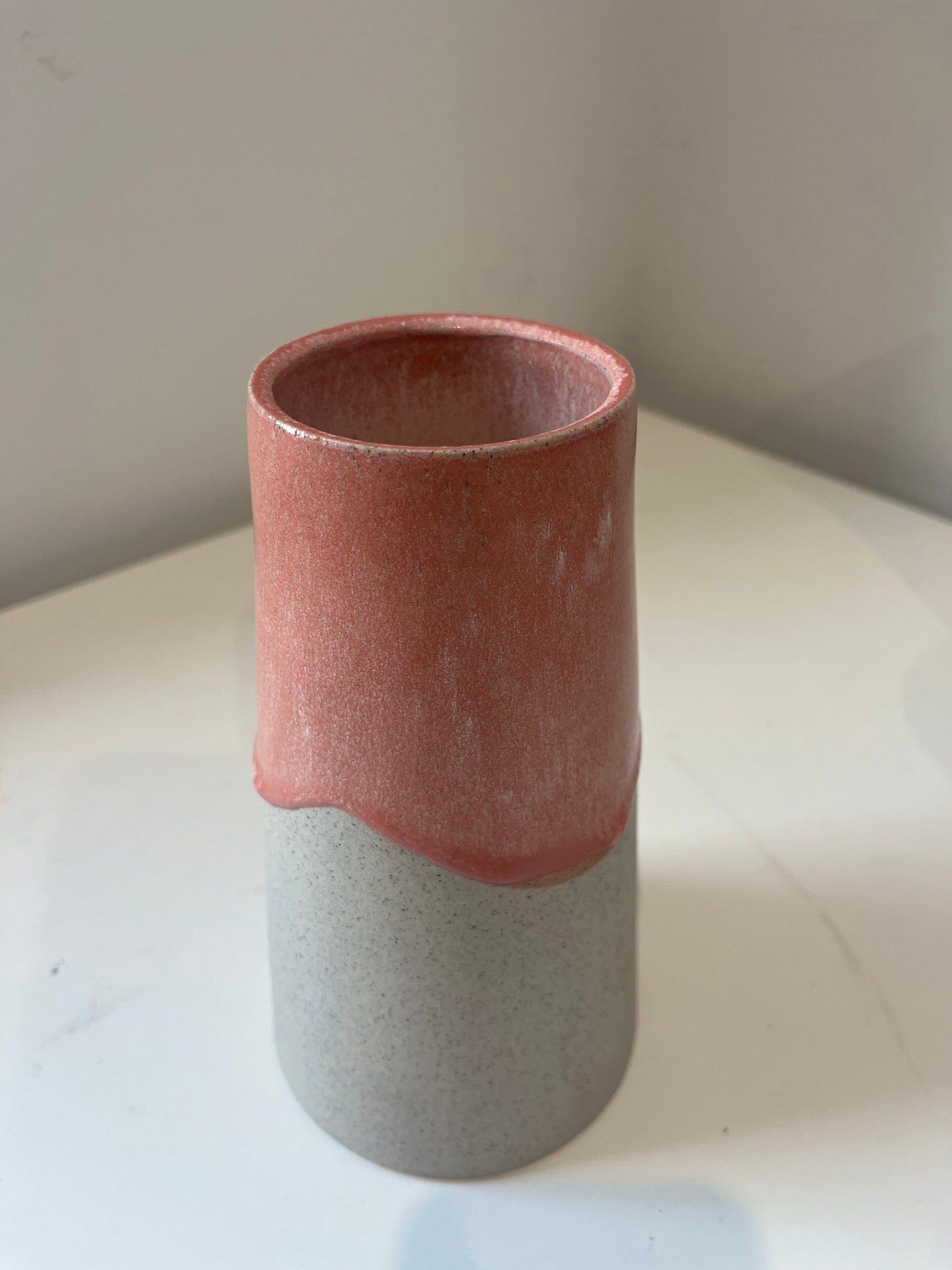 V shaped vase with glaze drips on a white background.