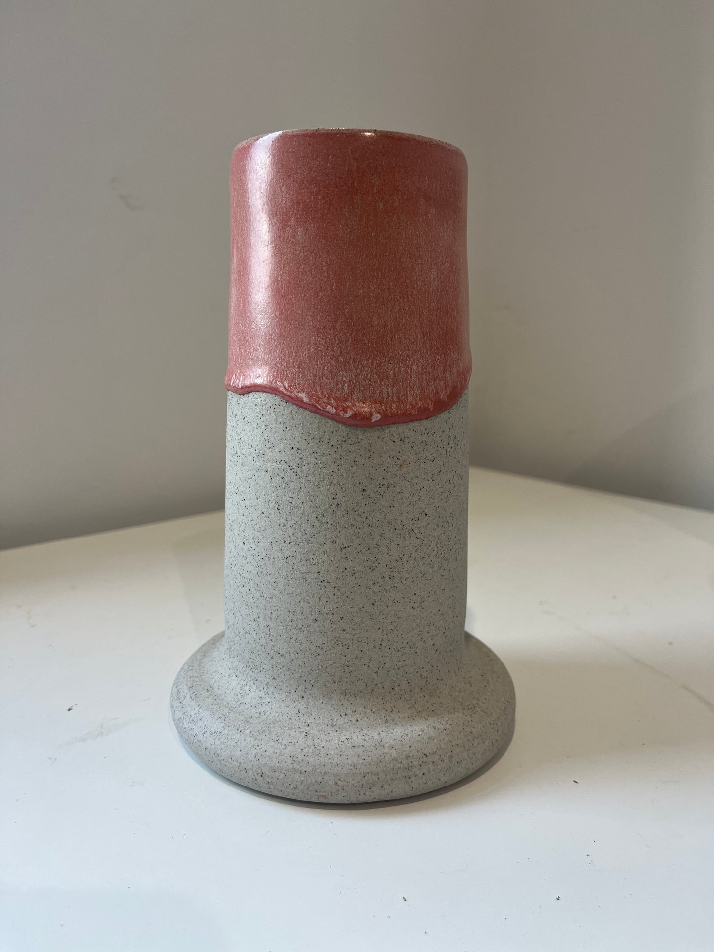 Cylindrical ceramic vase with a two-tone design on a white surface.