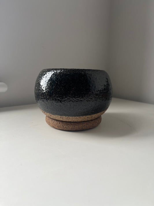 Black ceramic bowl with a textured surface on a white surface