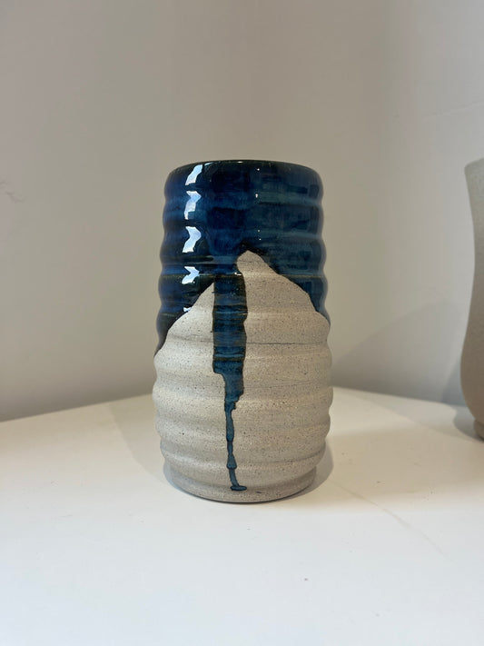 Ceramic vase with blue glaze and gray speckled clay on a white surface