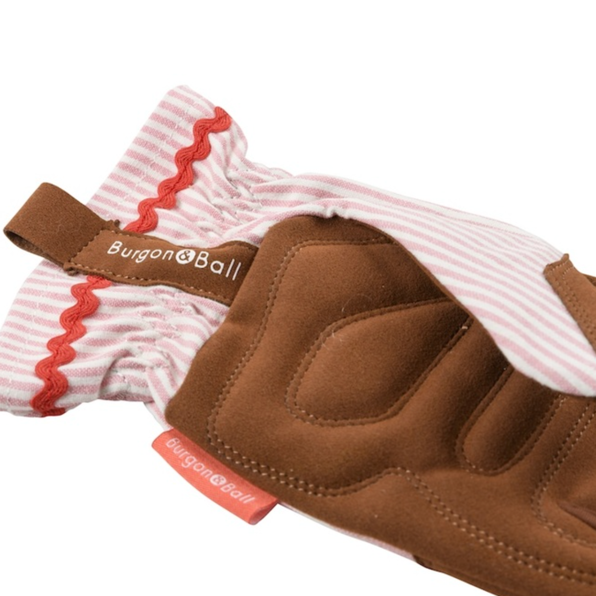 A close-up of a Burgon and Ball gardening glove showing the brown suede palm and the pink and white striped fabric cuff with red zigzag trim, on a white background.