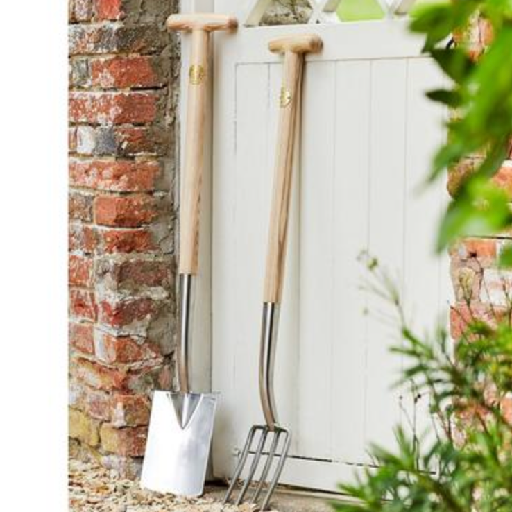 Gardening tools leaning against a white door with a brick wall background