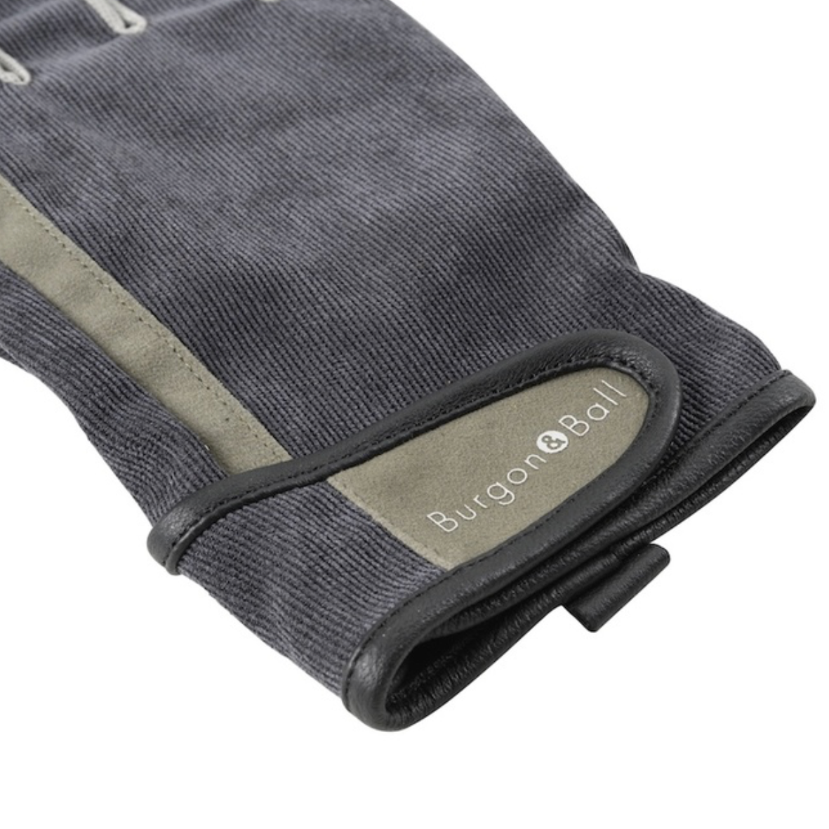 Close-up of a Burgon & Ball work glove in washed charcoal gray canvas with olive green suede-like panels and black trim, showing the brand logo on the cuff.