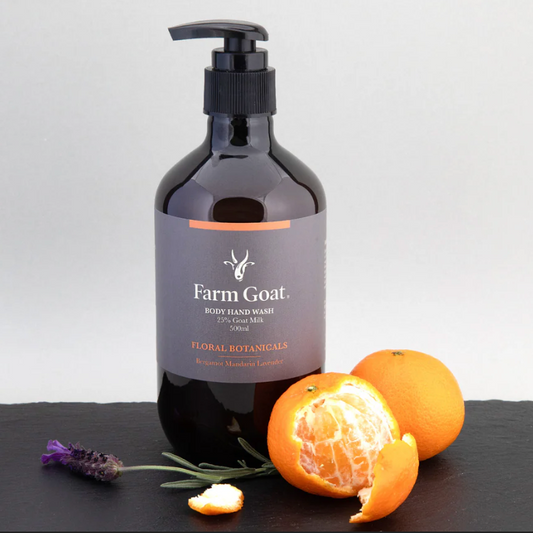 Bottle of Farm Goat skincare product with oranges and lavender on a black slate surface
