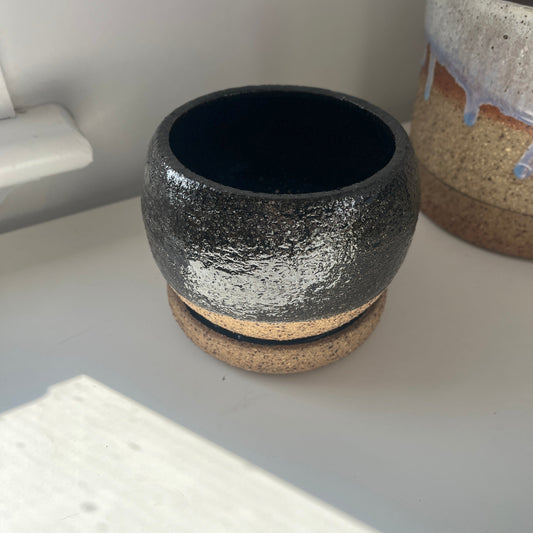 One ceramic pots on a white surface with a neutral background