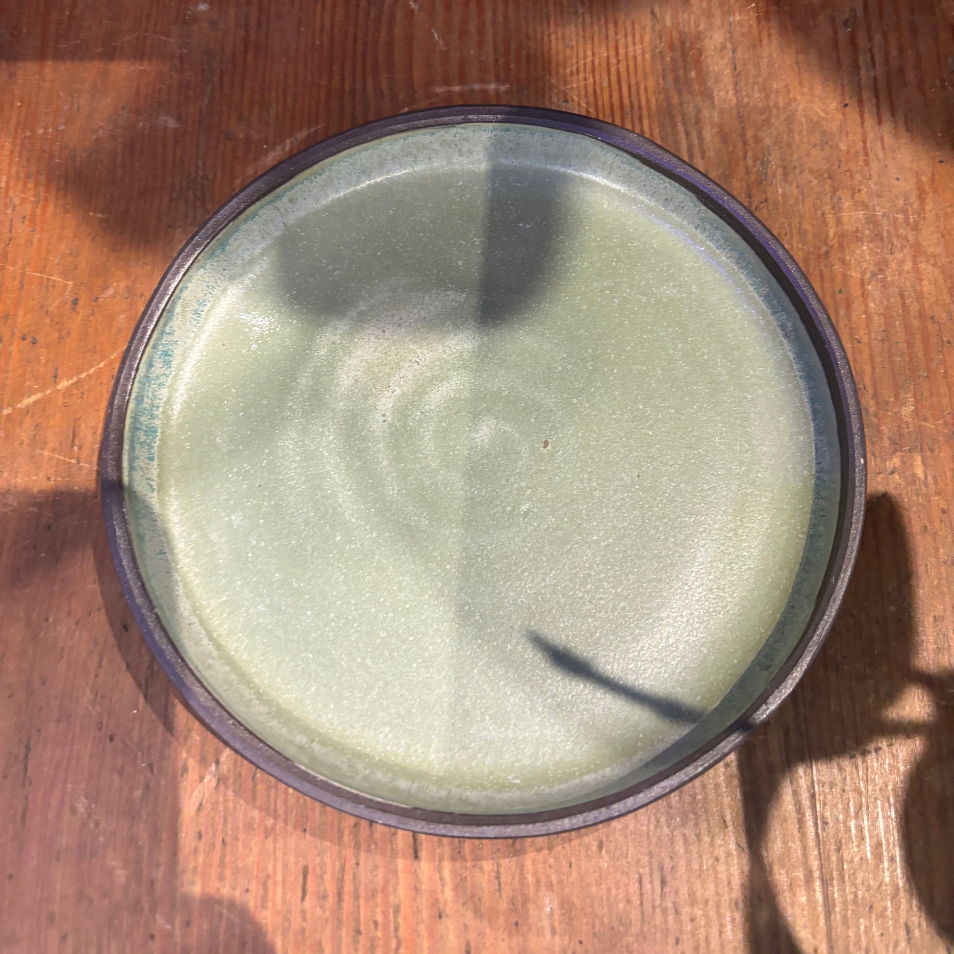 Green ceramic bowl on a wooden surface