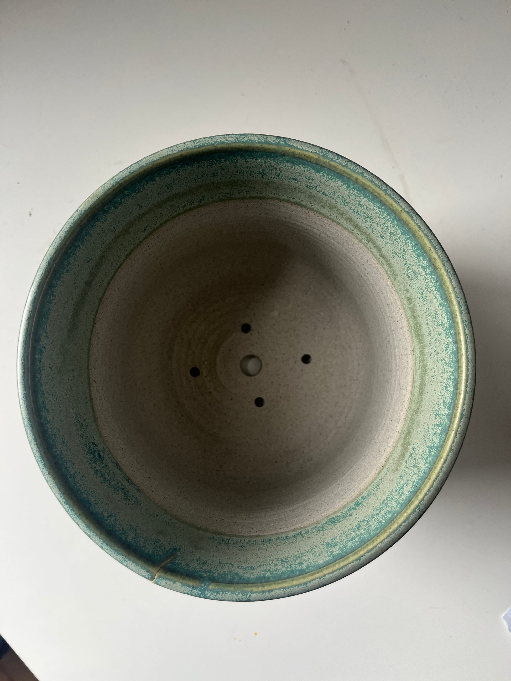 Ceramic pot with green rim on a white background