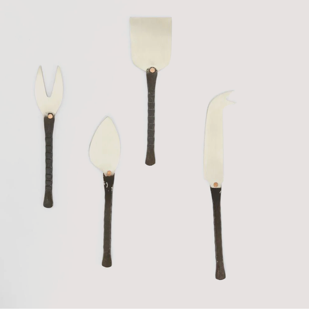 Set of four cheese tools with black handles on a light gray background