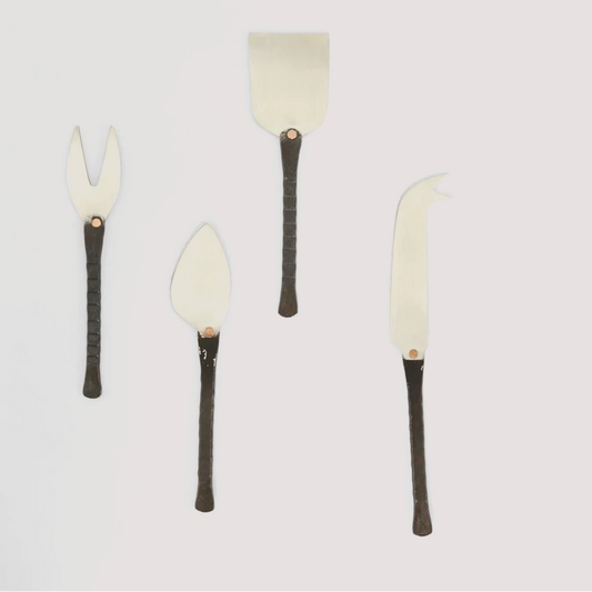 Set of four cheese tools with black handles on a light gray background