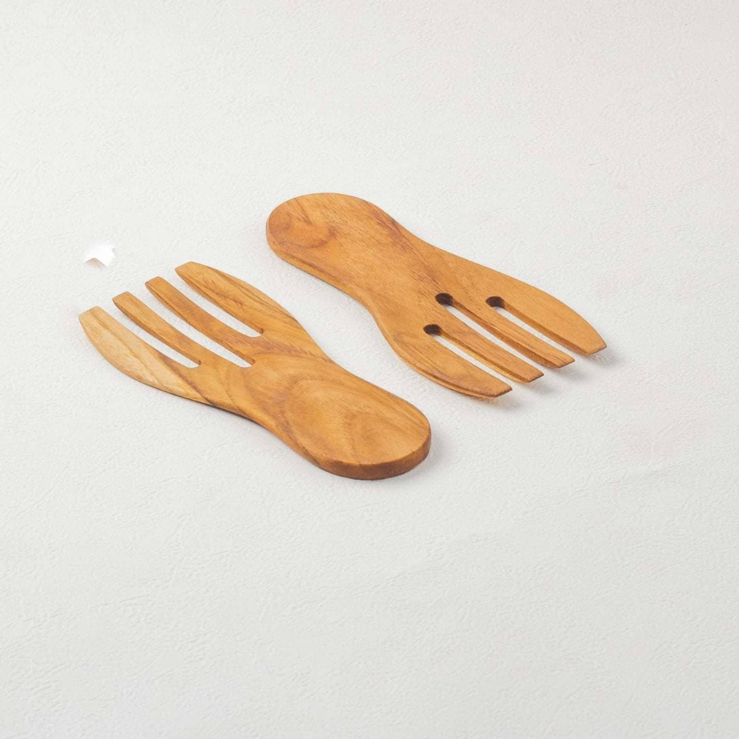 Wooden fork salad servers set on a light gray background