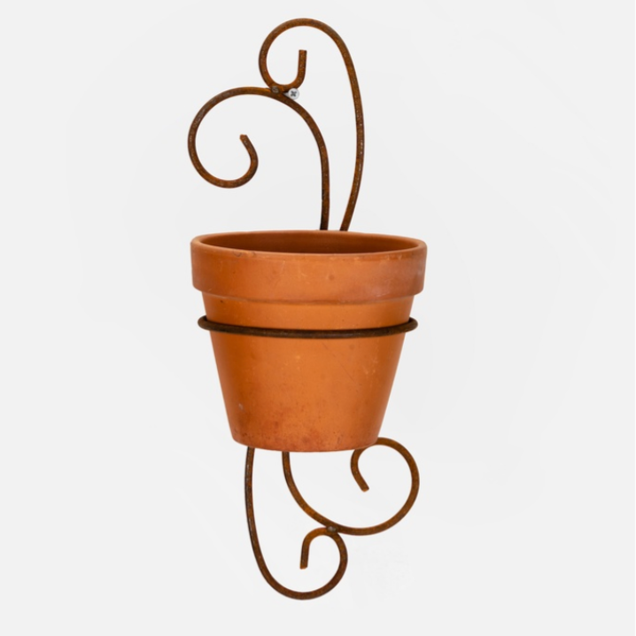 A terracotta-colored ceramic planter pot held by a rusted brown metal scroll hanger, shown against a plain white background.