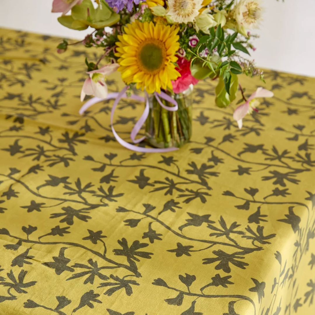 Floral arrangement on a yellow tablecloth with black floral pattern