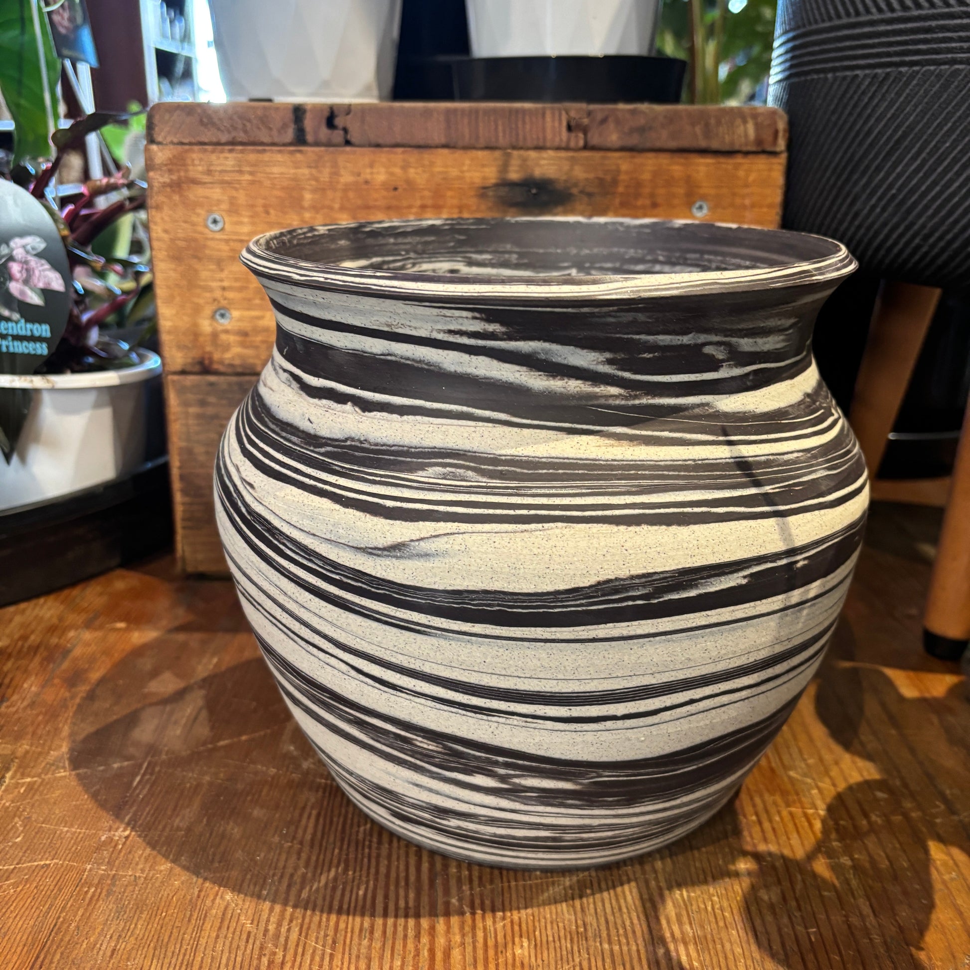 Charcoal and cream clay marbled pot on a wooden surface