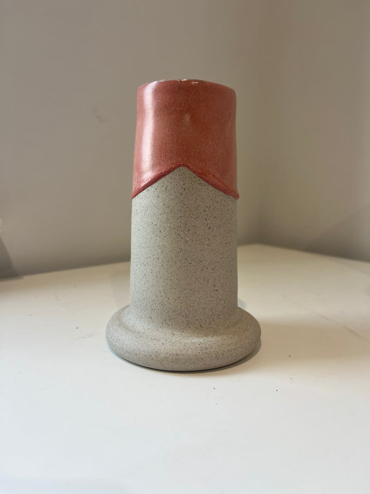 Two-toned ceramic vase with red and gray design on a white surface.