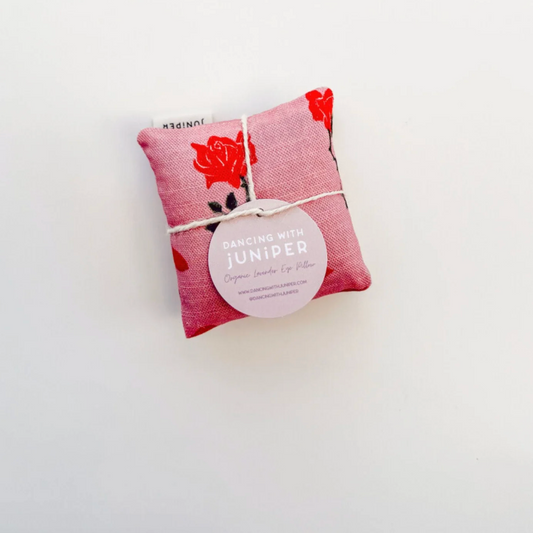 Pink decorative pillow with floral design and 'Baking with Juniper' label on a white background