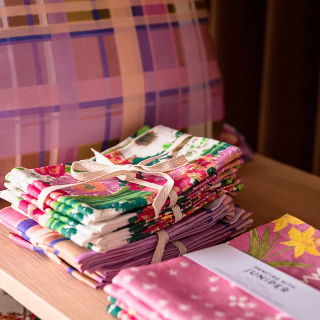 Stack of colorful fabric bundles tied with twine on a wooden surface.