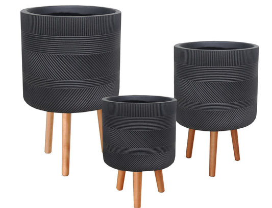 Three black textured planters with wooden legs on a white background