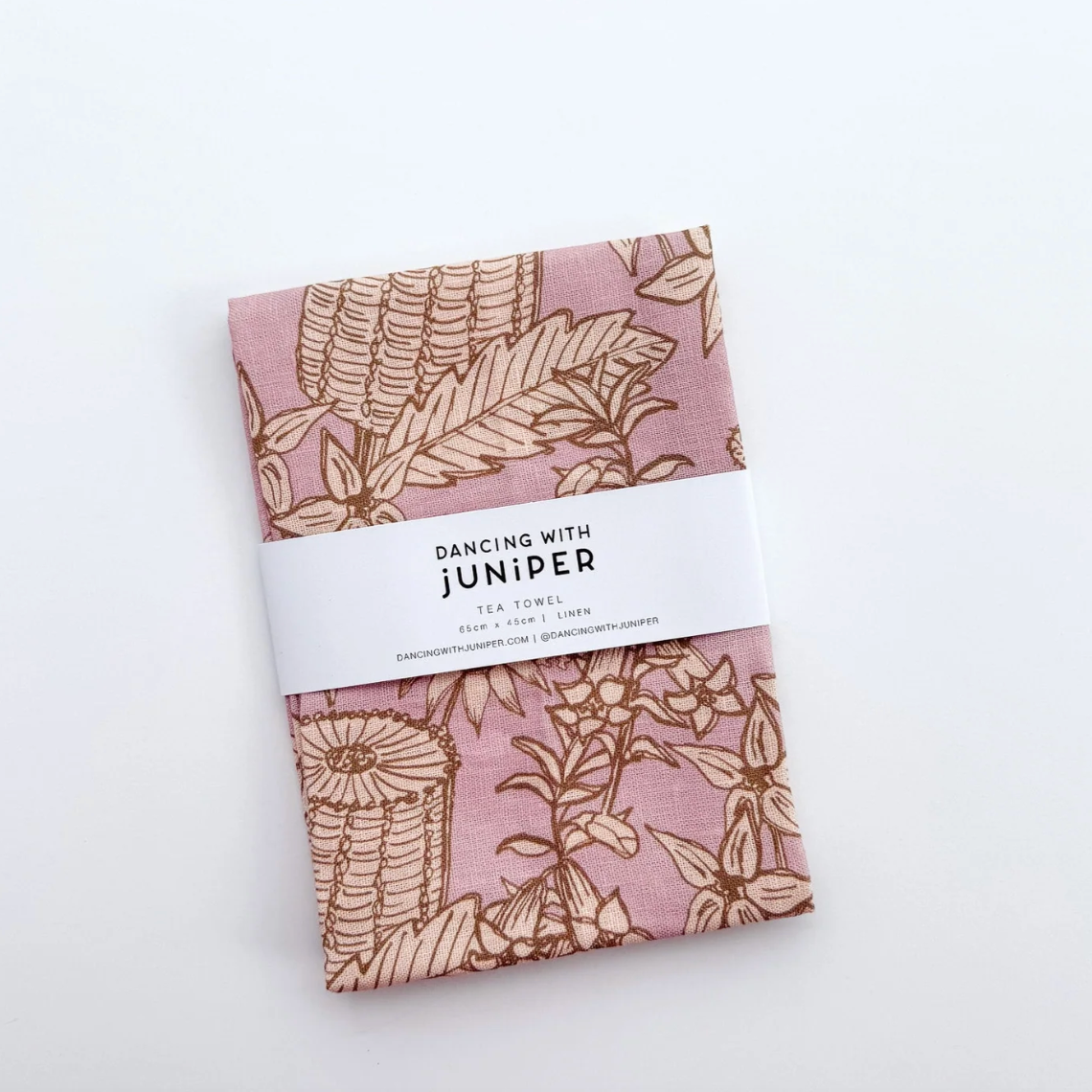 Pack of fabric tea towel with floral pattern and 'Dancing with Juniper' label on a white background