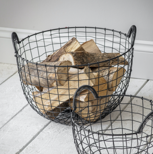 Wire baskets filled with firewood on a white floor.